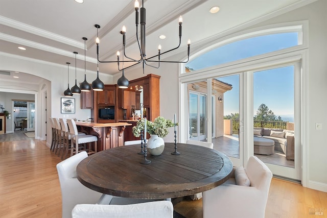 dining room with plenty of natural light, ornamental molding, a chandelier, and light wood-type flooring