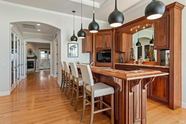 kitchen featuring hanging light fixtures, crown molding, and light hardwood / wood-style floors