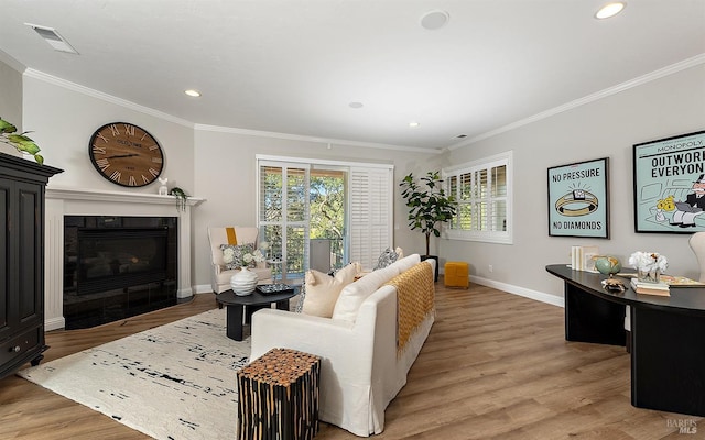 living room with light wood-type flooring, a fireplace, and crown molding