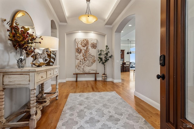 foyer with crown molding and light hardwood / wood-style floors