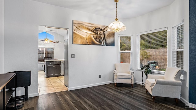 living area featuring hardwood / wood-style floors and ceiling fan with notable chandelier