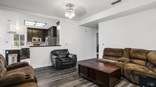 living room with ceiling fan, sink, and dark wood-type flooring