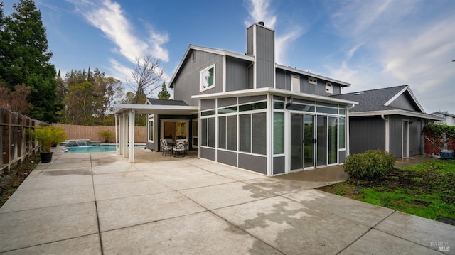 rear view of house featuring pool water feature, a fenced in pool, a patio area, and a sunroom