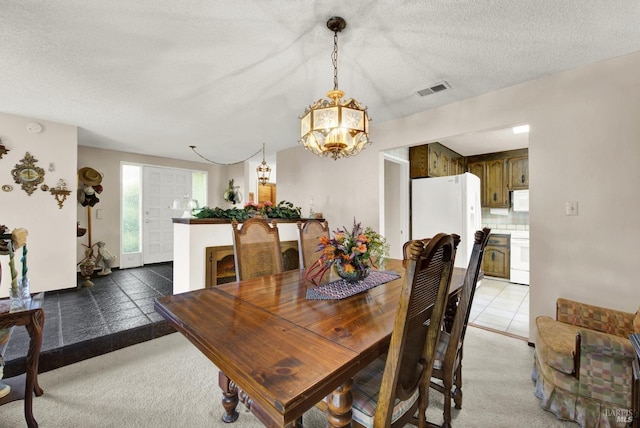 dining area with a textured ceiling, dark tile patterned flooring, and a notable chandelier