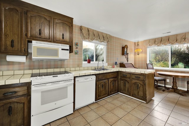 kitchen featuring kitchen peninsula, tile counters, white appliances, and sink