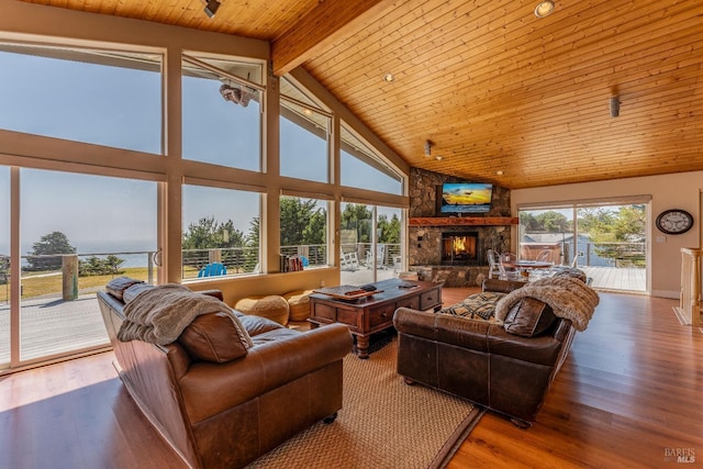 living room with beam ceiling, a stone fireplace, high vaulted ceiling, and wood-type flooring