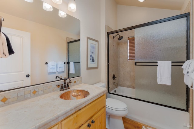 bathroom with toilet, bath / shower combo with glass door, vaulted ceiling, and vanity