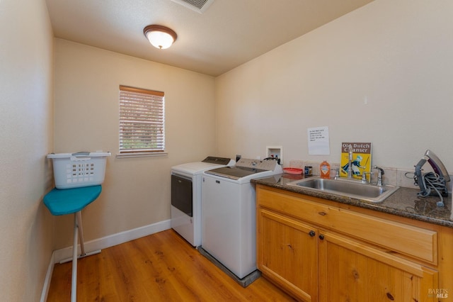 laundry area featuring cabinets, sink, washer and dryer, and light hardwood / wood-style floors