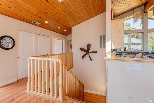 stairway featuring lofted ceiling with skylight, hardwood / wood-style floors, wooden ceiling, and sink