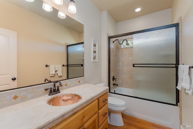 full bathroom with tasteful backsplash, vanity, hardwood / wood-style flooring, enclosed tub / shower combo, and toilet