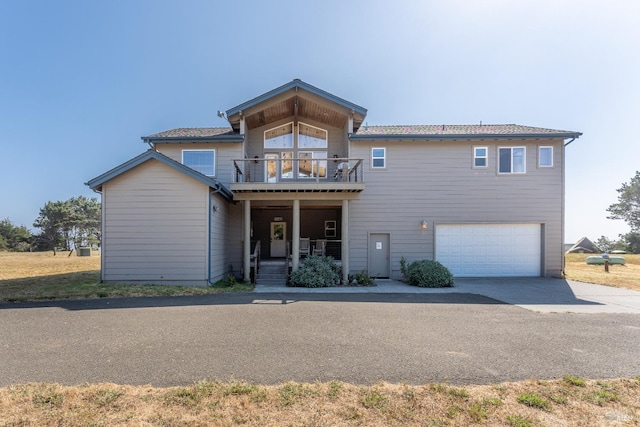 view of front facade featuring a balcony, covered porch, a garage, and concrete driveway