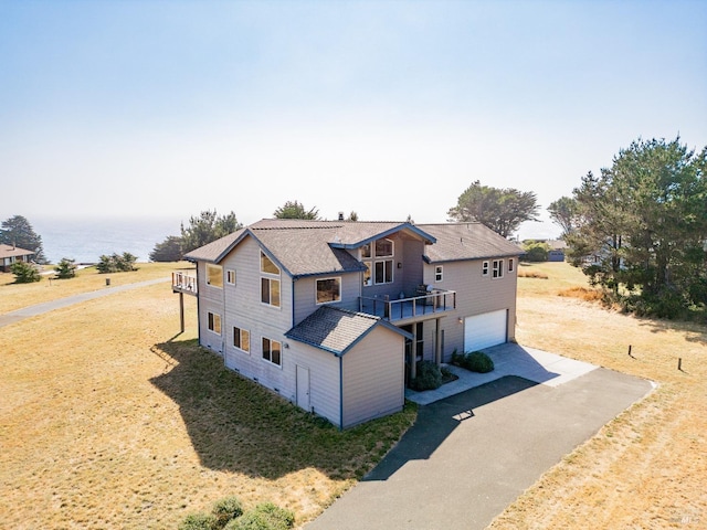 view of front facade featuring a garage, a water view, and a front lawn