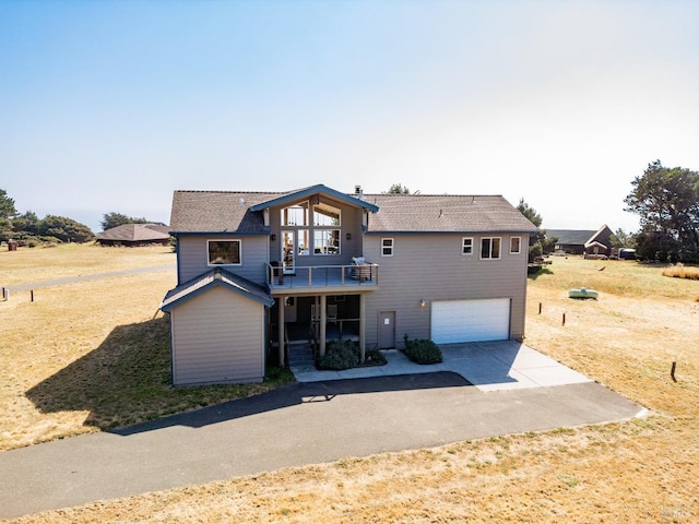 back of house featuring a yard, a balcony, and a garage