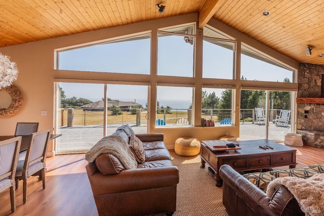 living room featuring wooden ceiling, wood finished floors, beamed ceiling, a fireplace, and high vaulted ceiling