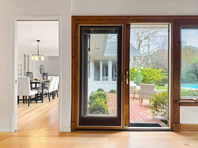 doorway with an inviting chandelier and light hardwood / wood-style flooring