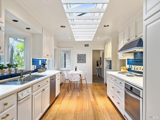 kitchen featuring white cabinetry, tasteful backsplash, stainless steel appliances, light hardwood / wood-style floors, and exhaust hood