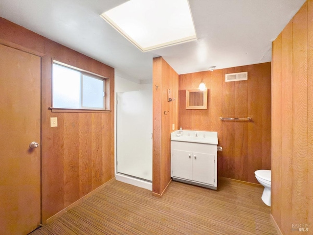 bathroom with vanity, walk in shower, toilet, and wood walls