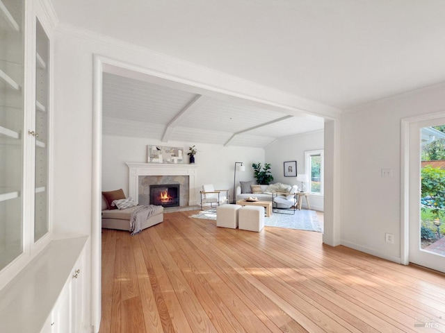 living room featuring lofted ceiling with beams, plenty of natural light, a fireplace, and light hardwood / wood-style floors