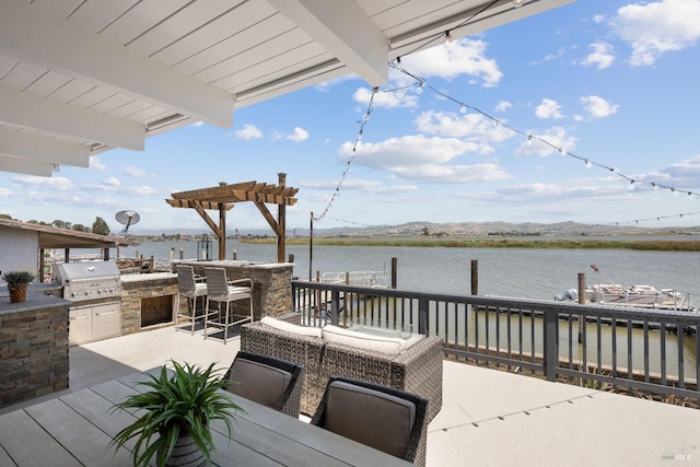 view of patio / terrace with exterior bar, an outdoor kitchen, a water view, and grilling area