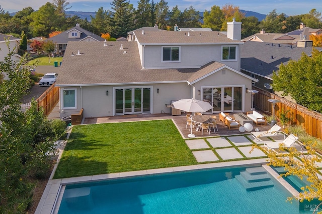 back of property featuring a yard, a patio, and a fenced in pool