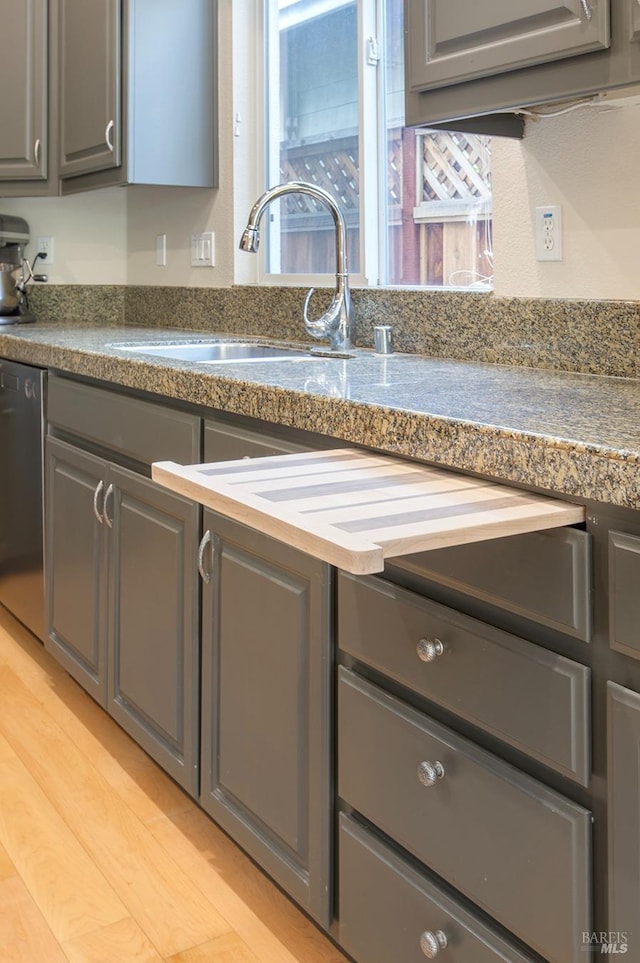 kitchen with dishwasher, gray cabinets, sink, and light hardwood / wood-style flooring