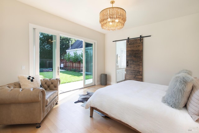 bedroom featuring access to exterior, light wood-type flooring, a barn door, and an inviting chandelier