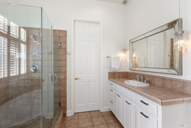 bathroom featuring tile patterned floors, a shower with door, and vanity