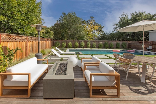 view of pool with an outdoor living space with a fire pit and a deck