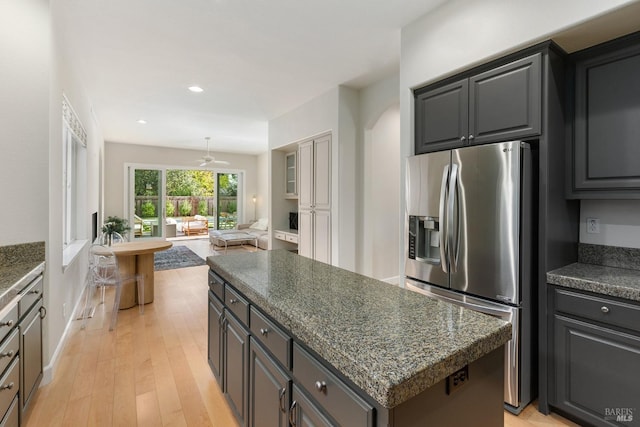 kitchen with gray cabinetry, ceiling fan, a center island, stainless steel fridge, and light wood-type flooring