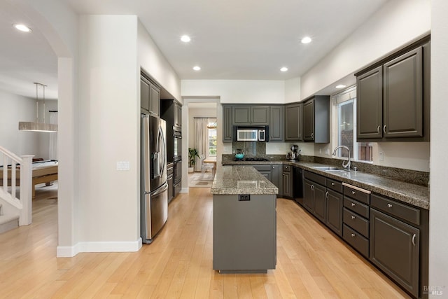 kitchen with a center island, dark stone counters, sink, light hardwood / wood-style floors, and stainless steel appliances