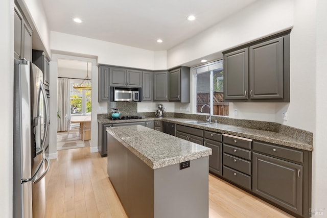 kitchen with gray cabinetry, stainless steel appliances, sink, a center island, and light hardwood / wood-style floors