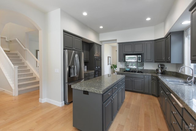 kitchen featuring sink, gray cabinets, a kitchen island, black appliances, and light wood-type flooring