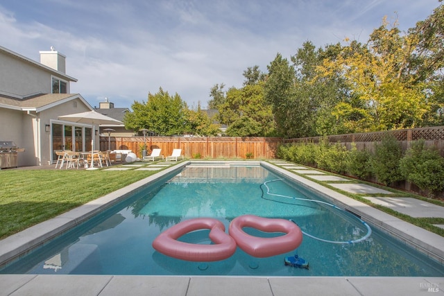 view of swimming pool with a lawn, grilling area, and a patio