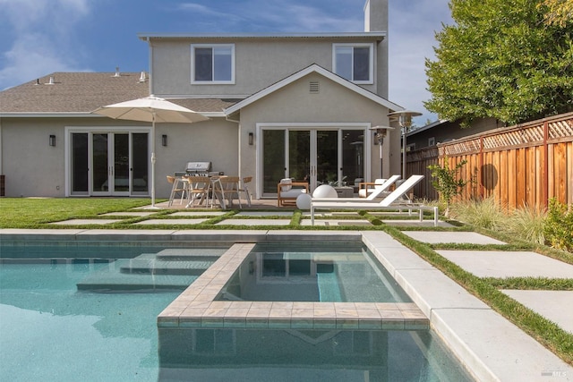 rear view of house with a patio and a pool with hot tub