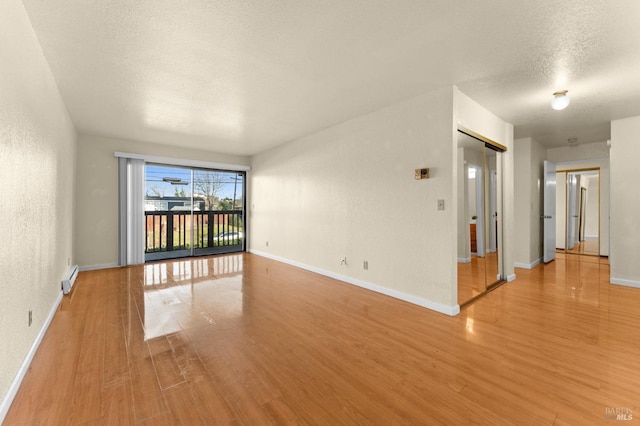 unfurnished room featuring a baseboard radiator, a textured ceiling, and light wood-type flooring