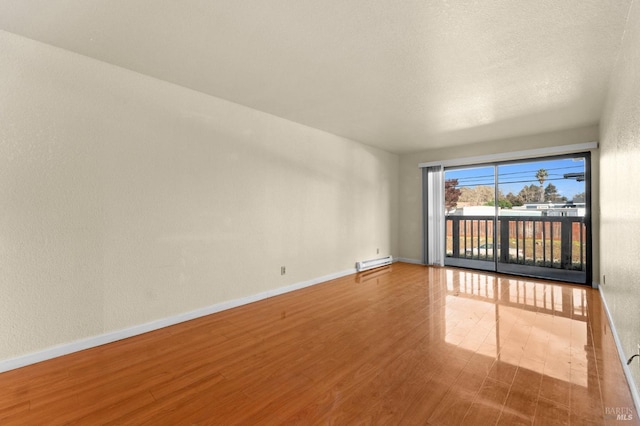 unfurnished room featuring a baseboard radiator and hardwood / wood-style floors