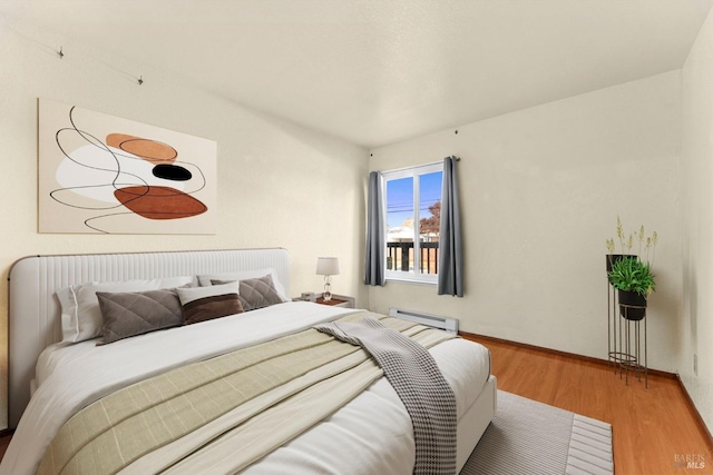 bedroom with wood-type flooring and a baseboard heating unit