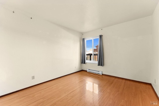 spare room with baseboard heating and hardwood / wood-style flooring