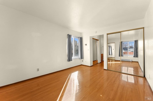 spare room with hardwood / wood-style flooring, a baseboard radiator, and a healthy amount of sunlight