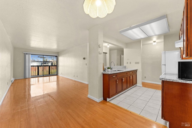 kitchen featuring light stone counters, sink, light hardwood / wood-style floors, and ceiling fan