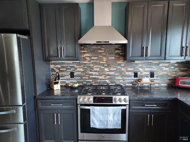 kitchen with decorative backsplash, wall chimney range hood, stainless steel appliances, and dark stone counters