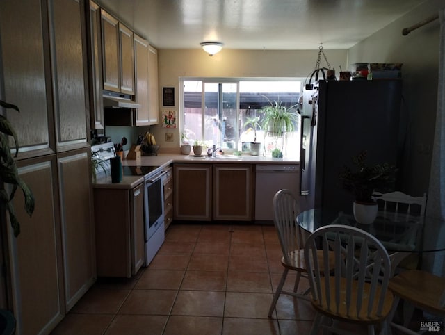 kitchen with dark tile patterned floors, white appliances, and sink