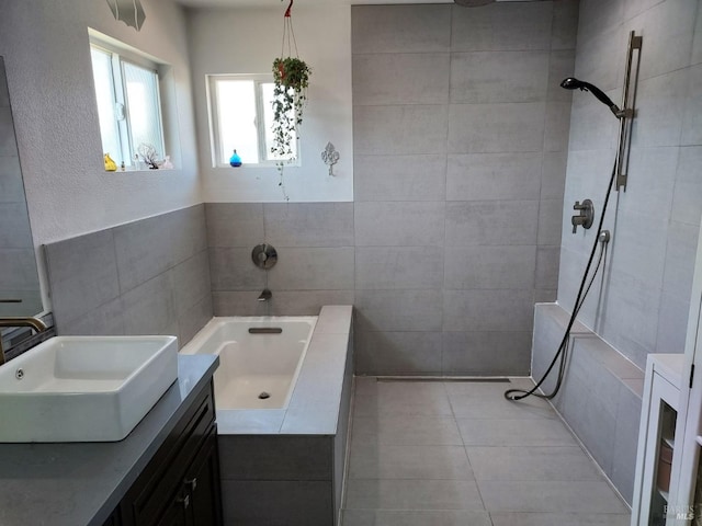 bathroom with tile patterned flooring, vanity, shower with separate bathtub, and tile walls