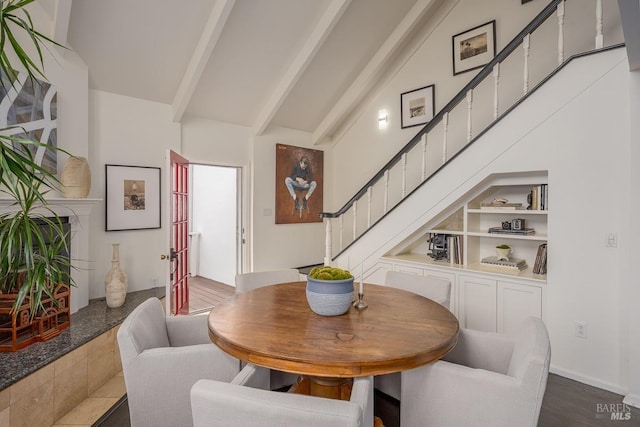 dining space with built in shelves, beam ceiling, dark wood-type flooring, and high vaulted ceiling