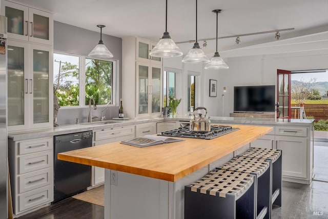 kitchen featuring a center island, butcher block counters, white cabinetry, and black dishwasher