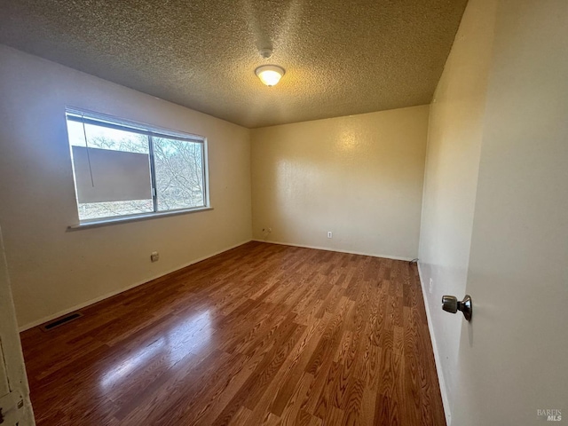 unfurnished room featuring a textured ceiling, wood finished floors, and visible vents