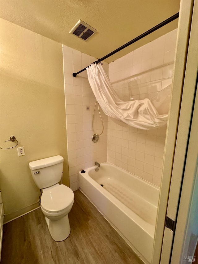 bathroom featuring shower / tub combo with curtain, visible vents, toilet, a textured ceiling, and wood finished floors