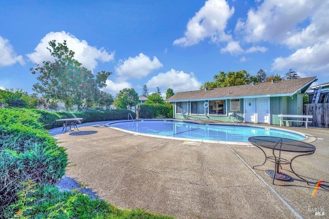 community pool with a patio area and fence