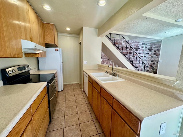 kitchen featuring a textured ceiling, under cabinet range hood, white appliances, a sink, and light countertops