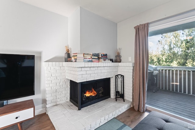 living room with wood-type flooring and a brick fireplace